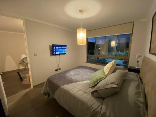Un dormitorio con una cama con ventana y un televisor. en Extraordinario depto ejecutivo, en Los Ángeles