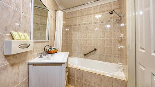 a bathroom with a sink and a bath tub at Canowindra Riverview Motel in Canowindra