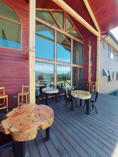 a wooden deck with tables and chairs on a building at Morrena Lodge in Torres del Paine