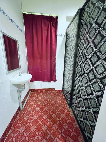 a bathroom with a sink and a red shower curtain at MJ inn in Ranau
