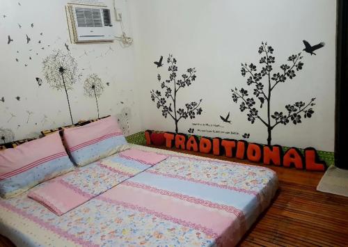 a bedroom with a bed with the word traditional on the wall at Alona's Traditional Filipino Home near 100 Islands Wharf in Alaminos