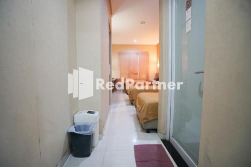 a corridor of a room with a bed and a bathroom at Tirta Mansion Lippo Karawaci Mitra RedDoorz in Karawaci