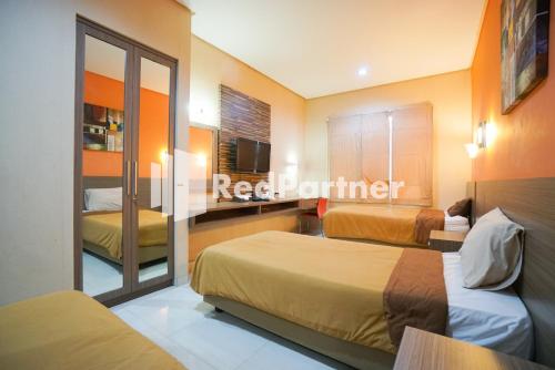 Habitación de hotel con 2 camas y espejo en Tirta Mansion Lippo Karawaci Mitra RedDoorz, en Karawaci