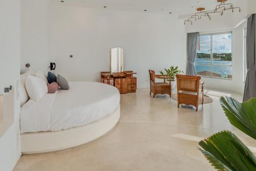 ein weißes Wohnzimmer mit einem weißen Bett und Stühlen in der Unterkunft Ampersand Resort in Bophut 