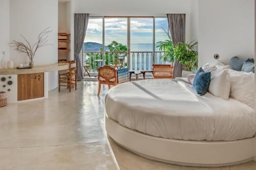 a large white bed in a room with a balcony at Ampersand Resort in Bophut 