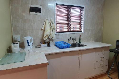 eine Küchentheke mit einem Waschbecken und einem Fenster in der Unterkunft Jakaranda Cabin - Self Catering Apartment in Secunda