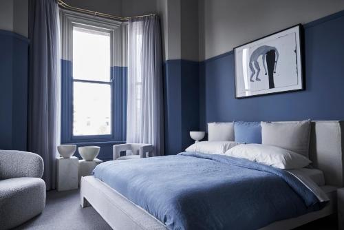 a blue bedroom with a bed and a chair at Hotel Vera Ballarat in Ballarat