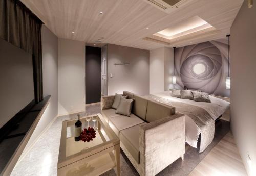 a bedroom with a bed and a couch and a table at Hotel Cocoon -Urban Luxury- in Suka