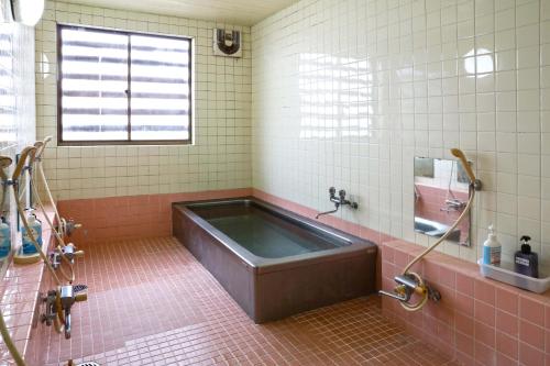 y baño con azulejos rosados y bañera grande. en Lodge Shosen, en Otari