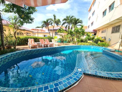 uma grande piscina com cadeiras e um edifício em BUTTERFLY GARDEN BOUTIQUE RESIDENCE by Luxury View EX LG Apts and Villas, A Lifestyle Destination 1 to 3 bedroom units 110 to 190 sqmtr, 2 FULL Bathrooms, Rain shower, Complete kitchen, FREE Fast Fiber WIFI, 55" SMART TVs, 24-7 Staff, SPA BATH, FREE BBQ em South Pattaya