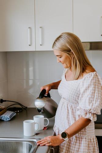 a woman standing in a kitchen preparing cups at Mudgee Valley Park in Mudgee