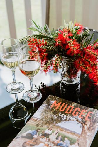 a table with two glasses of wine and a vase of flowers at Mudgee Valley Park in Mudgee