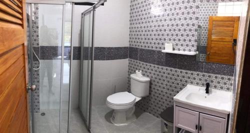 a bathroom with a toilet and a shower and a sink at Villa MILTONIA in Ban Ai Dao