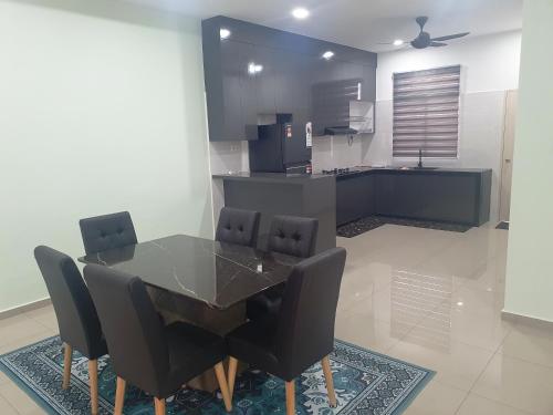 a dining room table with black chairs and a kitchen at RR Homestay in Kluang