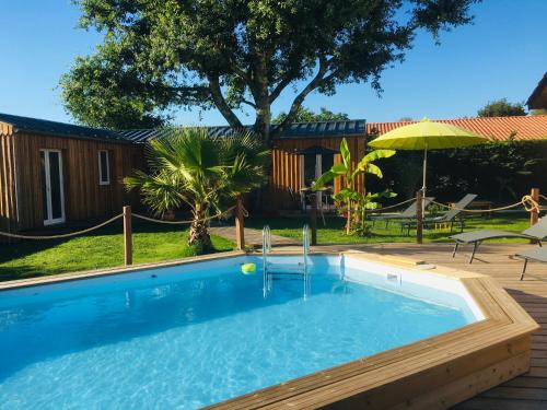 une piscine dans une cour avec un parasol dans l'établissement les petits chalets de kzo, à La Teste-de-Buch