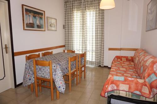 een woonkamer met een tafel en stoelen en een bank bij Homely apartment for up to 6 guests with pool in Porto Santa Margherita di Caorle