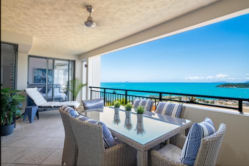 un patio con mesa, sillas y el océano en Pinnacles, en Airlie Beach