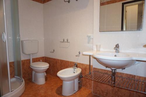een badkamer met een wastafel, een toilet en een spiegel bij Homely apartment for up to 6 guests with pool in Porto Santa Margherita di Caorle