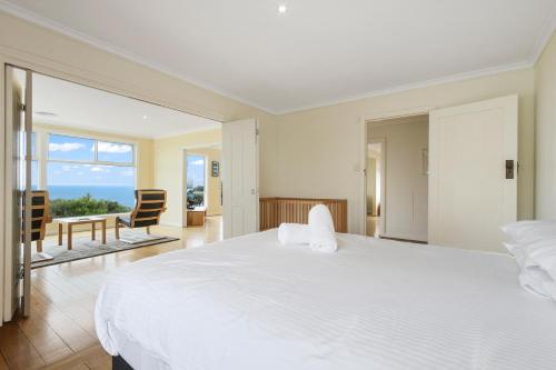 a bedroom with a large white bed and a balcony at Lake Tyers Beach House in Lake Tyers