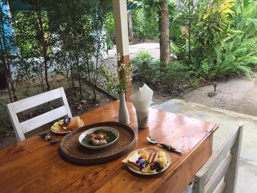 a wooden table with two plates of food on it at Baansuan Suksangob Farm Stay in Trang