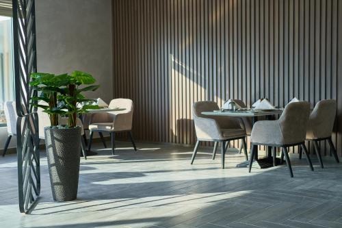 a dining room with a table and chairs and a plant at Hotel Holiday International in Sharjah
