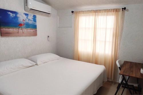 a bedroom with a white bed and a window at Casa Loma Flamingos Ixtapa in Ixtapa