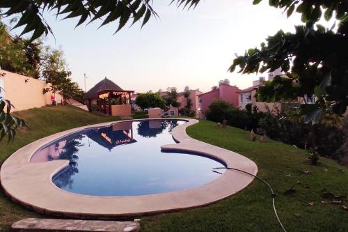 a swimming pool in the grass with a hose at Casa Loma Flamingos Ixtapa in Ixtapa