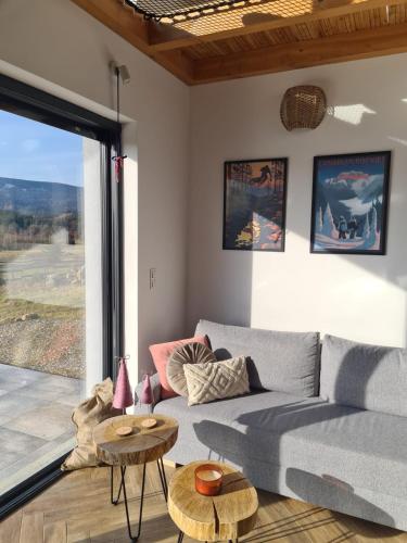 a living room with a couch and a large window at Lasosfera Lasówka in Lasowka