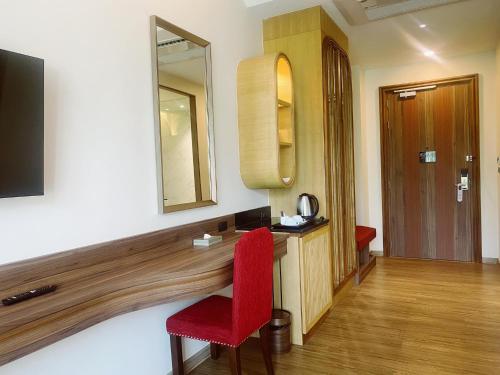 a room with a red chair and a mirror at Grand Lord Hotel & Residence - Khao chi chan Pattaya in Na Jomtien