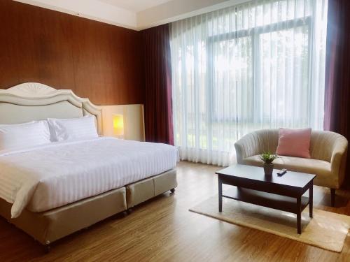 a bedroom with a bed and a chair and a table at Grand Lord Hotel & Residence - Khao chi chan Pattaya in Na Jomtien