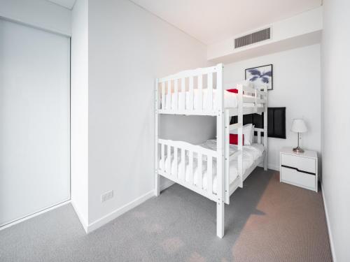 a white room with a bunk bed and a television at Lvl 24 Family apartment in the heart of CBD by Stylish Stays in Brisbane