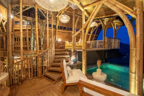 Bungbungan的住宿－Cliffside Bamboo Treehouse with Pool and View，一座带游泳池和木制天花板的房屋