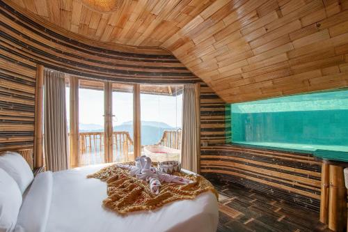 Bungbungan的住宿－Cliffside Bamboo Treehouse with Pool and View，一间卧室设有一张大床和一个大窗户