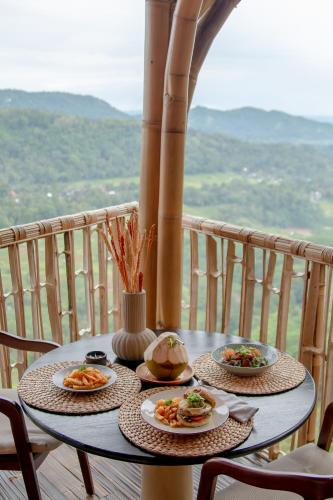 two plates of food on a table on a balcony at Cliffside Bamboo Treehouse with Heated Pool and View in Bungbungan