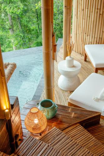 a wooden table with a vase on top of a porch at Cliffside Bamboo Treehouse with Heated Pool and View in Bungbungan