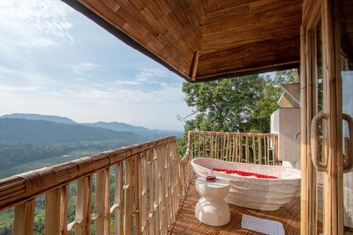 a porch with a large tub on a deck at Cliffside Bamboo Treehouse with Heated Pool and View in Bungbungan