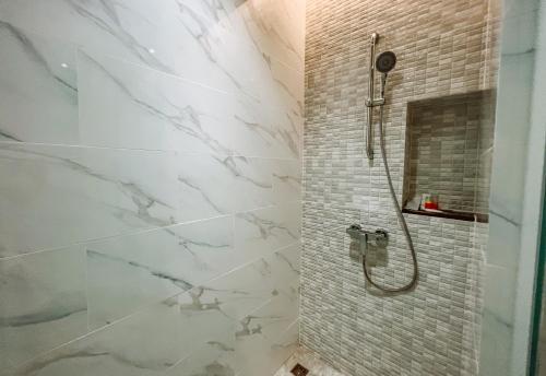 a bathroom with a shower with white marble tiles at Grand Lord Hotel & Residence - Khao chi chan Pattaya in Na Jomtien