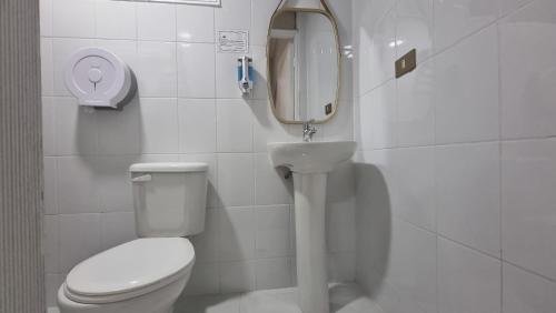a bathroom with a toilet and a sink and a mirror at Hotel Asturias in Viña del Mar