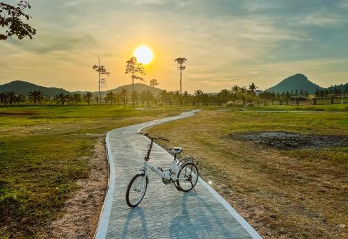 a bike parked on a path at sunset at Grand Lord Hotel & Residence - Khao chi chan Pattaya in Na Jomtien