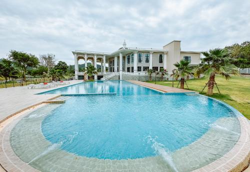 a large swimming pool in front of a house at Grand Lord Hotel & Residence - Khao chi chan Pattaya in Na Jomtien