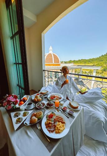 a man sitting in bed with a table full of food at Grand Lord Hotel & Residence - Khao chi chan Pattaya in Na Jomtien