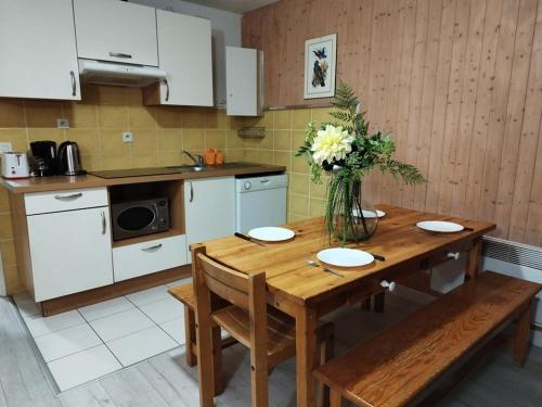 une cuisine avec une table en bois et un vase de fleurs dans l'établissement Appartement lumineux 8 pers, pied des pistes, 2 ch, balcon, cuisine équipée, proche commerces et sports - FR-1-262-91, à Forest des Baniols