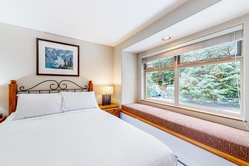 a bedroom with a white bed and a window at Lake Placid Coach House 17 in Whistler