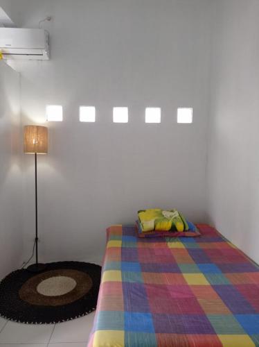 a bedroom with a bed with a colorful blanket at Mommy Cafe Guesthouse in Pangandaran