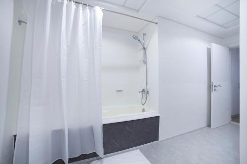 a white bathroom with a shower and a tub at Lux Living on Palm Jumeirah With Beach Access & Complimentary Golf in Dubai