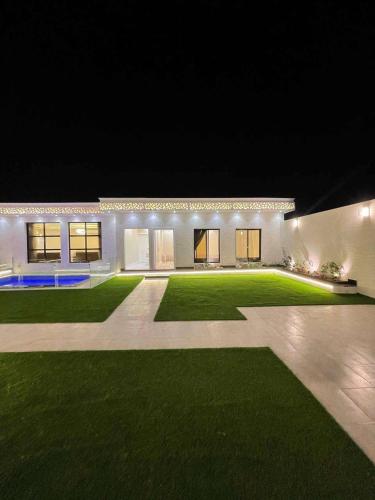 a house with a large yard at night at شالية الجوهرة in Taif