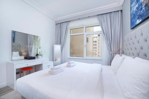 a white bedroom with a large white bed and a window at Lux Living on Palm Jumeirah With Beach Access & Complimentary Golf in Dubai