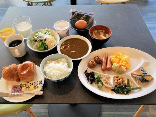 a table with plates of food and bowls of food at Green Rich Hotel Kyoto Station South (Artificial hot spring Futamata Yunohana) in Kyoto