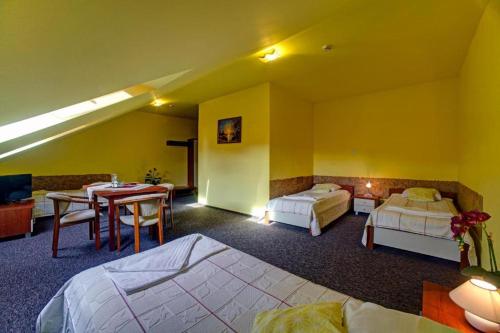 a hotel room with two beds and a table and a dining room at Hotel "Piast" in Tuczempy