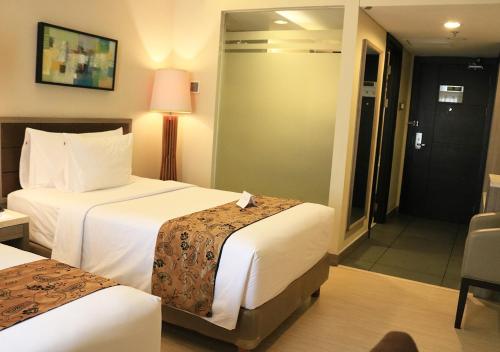 a hotel room with two beds and a sliding glass door at BW Kemayoran Hotel & Convention Powered by Archipelago in Jakarta
